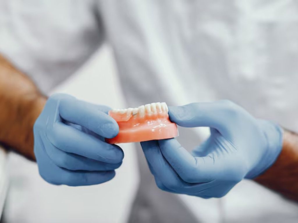 dentist holding a partial denture to demonstrate tooth replacement for missing teeth